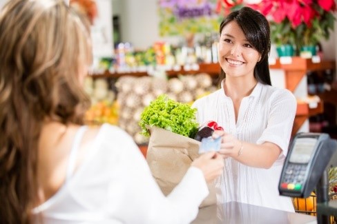 a woman handing a payment card to a cashier