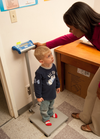 a child standing on a scale to have his weight measured